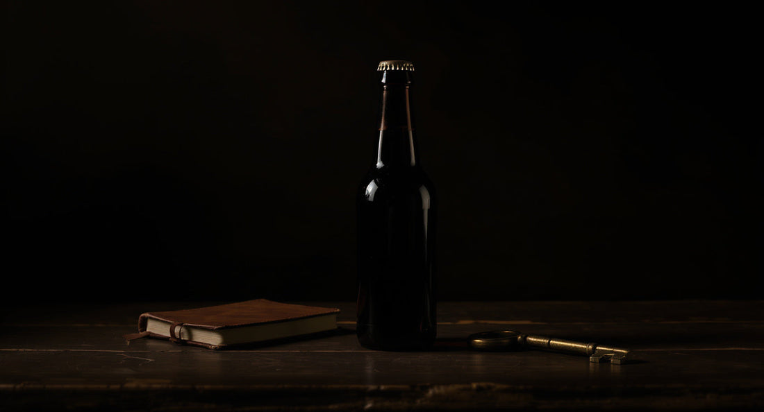 Bierflasche mit Lederbuch und Messingschlüssel im warmen Licht