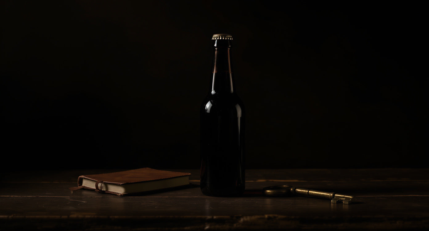 Bierflasche mit Lederbuch und Messingschlüssel im warmen Licht